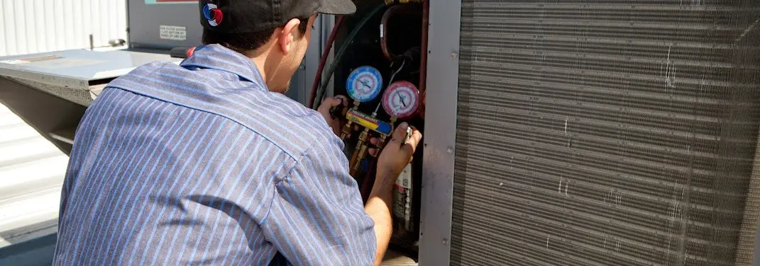 HVAC technician servicing a condenser unit in Troutdale
